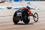 Atletka na závodní dráze pro vozíčkáře v paraatletické soutěži