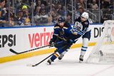 Adam Lowry z Winnipegu (v bílém) se snaží vypíchnout puk obránci St. Louis Justinu Faulkovi