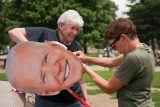 Ženy připravují banner s tváří exprezidenta Bidena na demonstraci v den vojenské přehlídky a Trumpových narozenin ve Washingtonu (14. června 2025)