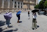 Turisté v Seville na jihu Španělska se chrání deštníky před sluncem