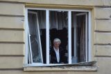 Obyvatel Lvova odstraňuje sklo z rozbitého okna svého bytu, které bylo poškozeno při útoku ruských dronů a raket