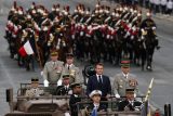 Francouzský prezident Emmanuel Macron stojí v velitelském voze s náčelníkem generálního štábu francouzských ozbrojených sil (CEMA) Thierrym Burkhardem během každoroční vojenské ceremonie k oslavě Dne dobytí Bastily na bulváru Champs-Elysées v Paříži, Francie, 14. července 2025