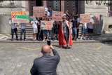 Šéf agentury Advertes fotí falešnou demonstraci. Několik účastníků drží bílý papír s QR kódem, který jim krátce předtím předal Leroy Weinrich a další pracovníci agentury