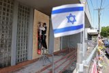 Člen židovské komunity připevňuje plakát na průčelí poškozené synagogy v Melbourne