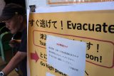 Varování před tsunami a výzva k evakuaci cestujících na nádraží ve městě Kamakura na japonském ostrově Honšú