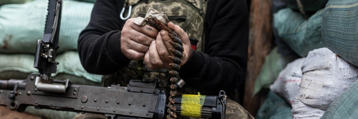 Ukrajinský voják nabíjí kulomet na bojové pozici v zákopu