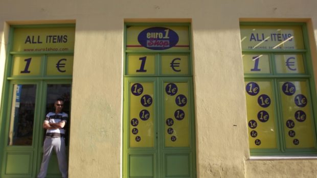 Muž stojí v centru Atén před obchodem, kde všechno stojí jedno euro.