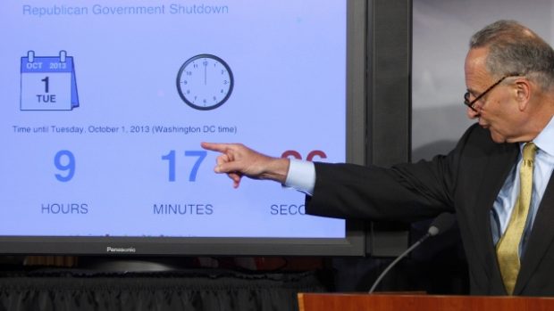 Americký senátor Chuck Schumer ukazuje při tiskové konferenci ve washingtonském Capitolu na odpočítávací hodiny.