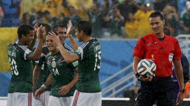Fotbalisté Mexika se radují z premiérového vítězství na MS nad výběrem z afrického kontinentu, oslavy z povzdálí sleduje hlavní rozhodčí Roldan