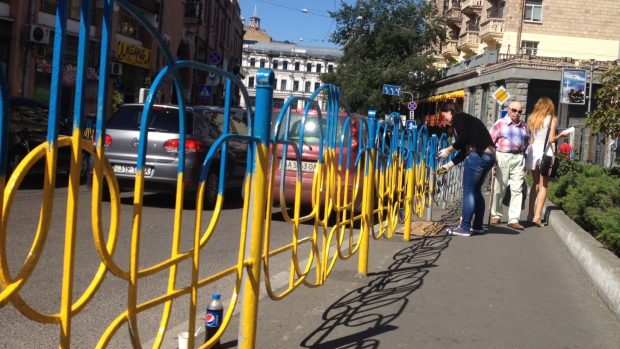 Dobrovolníci v ulicích Kyjeva natírají městský mobiliář na modro-žluto