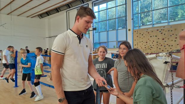 Jakub Jurka ukazuje příchozím dětem svou bronzovou medaili z letošní olympiády v Paříži