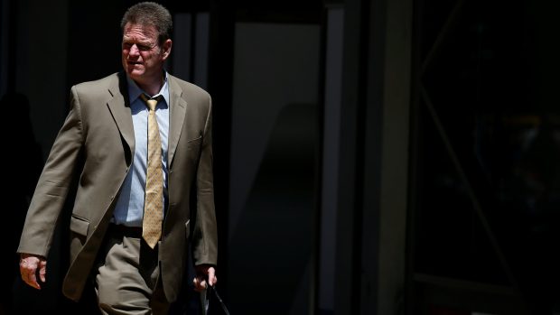 Muž v obleku prochází za slunečného dne New Yorkem