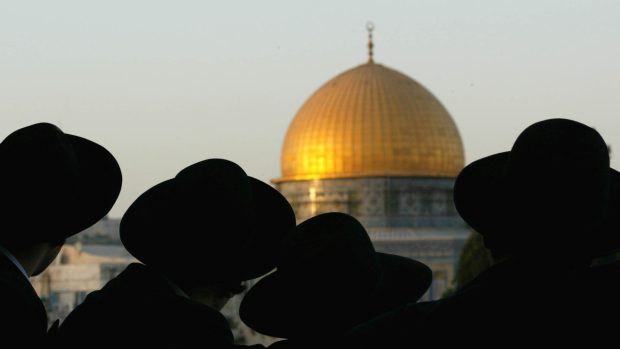 Siluety ultraortodoxních židů, za nimiž se rýsuje ikonická kupole Skalního dómu.