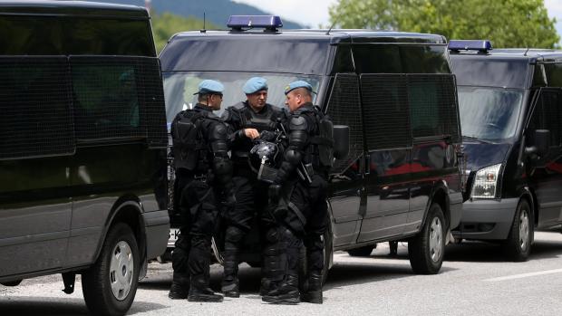 Příslušníci speciálních policejních jednotek poblíž autobusů s uprchlíky (mimo snímek) u města Konjic v Hercegovsko-neretvanském kantonu (18. května 2018).