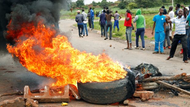 Demonstranti nedaleko hořící barikády před Harare na snímku z 15. ledna 2019.