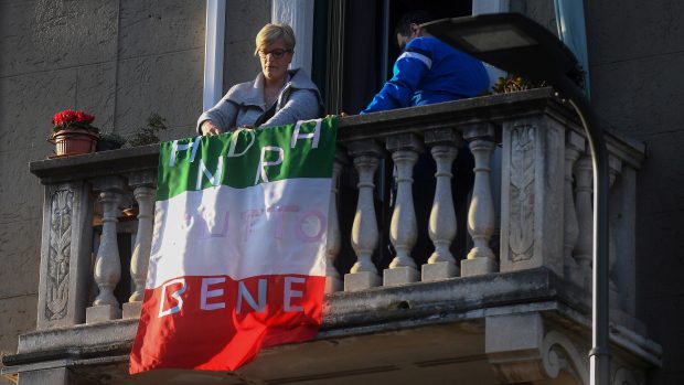 Žena vyvěsila na balkon vlajku s nápisem, že zase bude dobře.