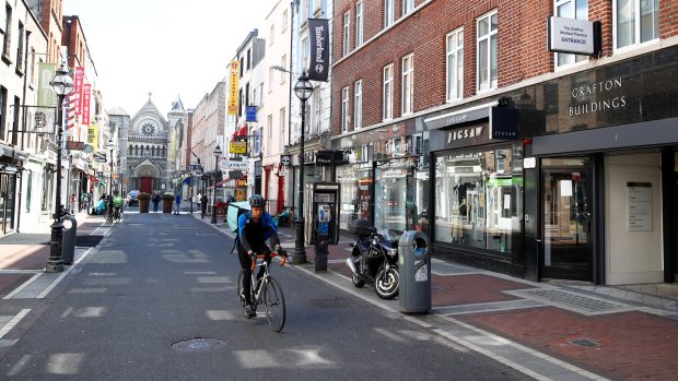 Poslíček rozvážející jídlo v jedné z poloprázdných ulic Dublinu.