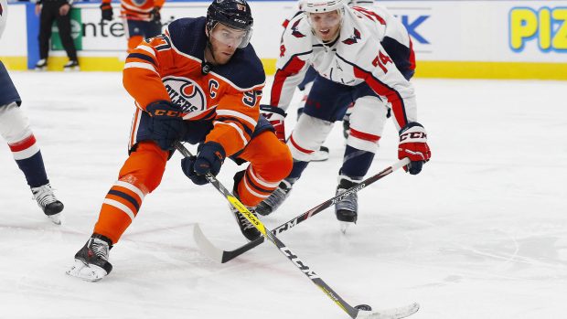 Nejproduktivnější hráč NHL Connor McDavid objíždí s pukem obránce Capitals Johna Carlsona