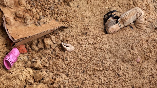 Tělo mrtvého civilisty, který byl společně s dalšími pohřben v masovém hrobě v ukrajinském městě Buča