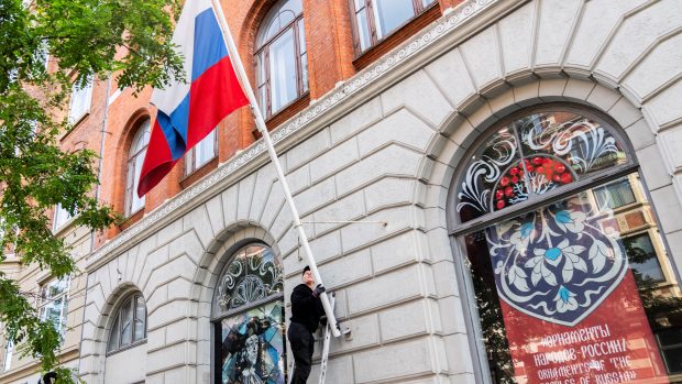 Muž sundává ruskou vlajku z Ruského domu v Kodani. Budova patři ruské ambasádě, která podléhá evropským sankcím (26. září 2023)