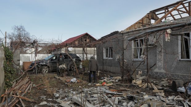 Obyvatelé Oděsy odstraňují trosky z dvorku svého domu, který byl poškozen během ruského dronového útoku 17. prosince 2023