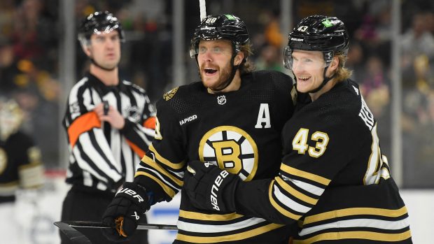 Pravé křídlo Boston Bruins David Pastrňák slaví s levým křídlem Dantonem Heinenem po vstřelení svého třetího gólu