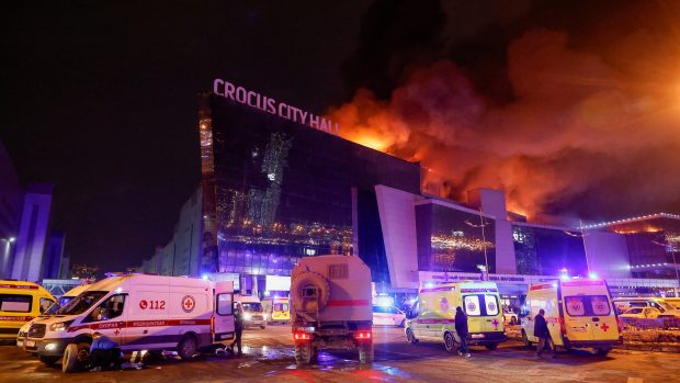 Vozidla ruských záchranných složek parkují u hořící koncertní haly Crocus City Hall po nahlášené střelbě, u Moskvy, Rusko, 22. března 2024