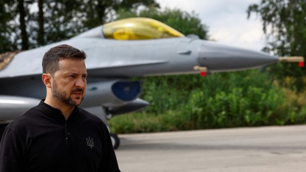 Ukrajinský prezident Volodymyr Zelenskyj hovoří s médii před bojovým letounem F-16 po oslavách Dne ukrajinského letectva uprostřed ruského útoku na Ukrajinu na neznámém místě na Ukrajině 4. srpna 2024