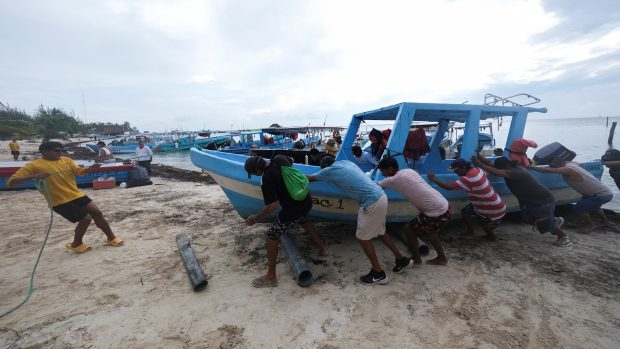 Lidé v mexickém Cancúnu vytahují před příchodem hurikánu Milton turistickou loď z vody (7. října 2024)