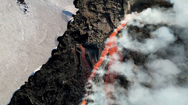 Sicilská sopka Etna se v poslední době projevuje mírnou aktivitu. Na snímku proud lávy pomalu klesá po zasněženém svahu a rozpouští sníh, který vytváří potok