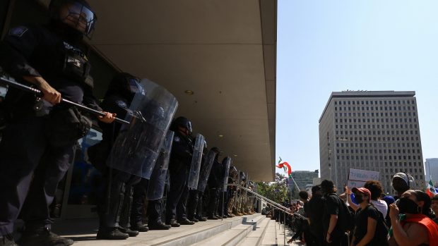 Demonstranti před budovou v Los Angeles, v níž sídlí řada federálních úřadů, nesli transparenty jako: „Stojím za všemi migranty“. Vchod střežili policisté a příslušníci Národní gardy