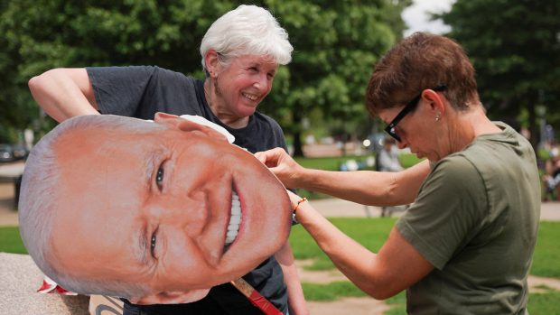 Ženy připravují banner s tváří exprezidenta Bidena na demonstraci v den vojenské přehlídky a Trumpových narozenin ve Washingtonu (14. června 2025)