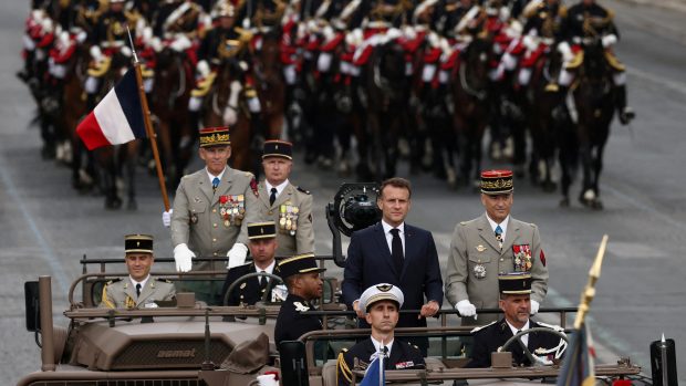 Francouzský prezident Emmanuel Macron stojí v velitelském voze s náčelníkem generálního štábu francouzských ozbrojených sil (CEMA) Thierrym Burkhardem během každoroční vojenské ceremonie k oslavě Dne dobytí Bastily na bulváru Champs-Elysées v Paříži, Francie, 14. července 2025