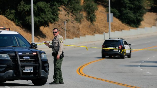 Policista úřadu šerifa v Los Angeles u žluté pásky blokující cestu k výcvikovému středisku Biscailuz Center Academy