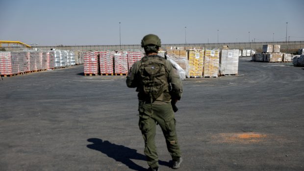 Izraelský voják stojí vedle balíků s humanitární pomocí, které čekají na převoz z Izraele do Gazy