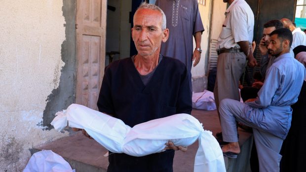 Palestinský muž nese mrtvé tělo oběti izraelského úderu na stany u Nemocnice mučedníků Al-Aksá ve městě Dajr Balah (31. července 2025)