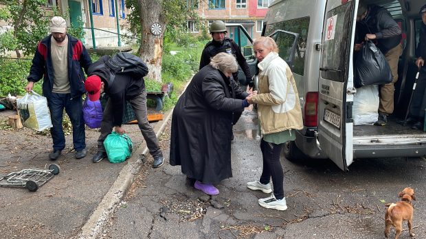 Při nakládání uprchlíků do auta jsou z dálky slyšet detonace