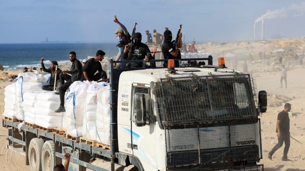 Palestinci z ozbrojených klanů jedou na kamionu s humanitární pomocí