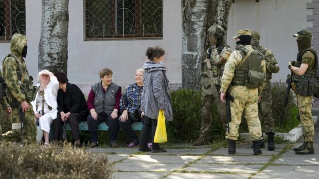 Místní obyvatelé se baví se skupinou ruských vojáků v Chersonu (foto z 20. května, pořízené během cesty organizované ruským ministerstvem obrany)