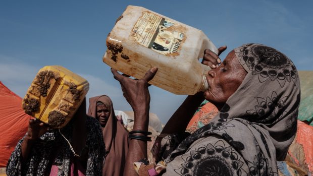 Šedesátiletá žena pije v somálském městě Baidoa vodu ze špinavého barelu