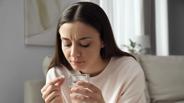 Žena s potratovou pilulkou a sklenicí vody (ilustrační foto)