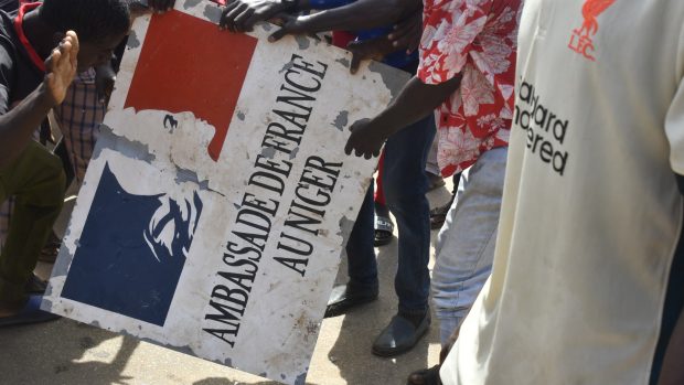 Demonstranti drží nápis stržený z francouzského velvyslanectví v Niamey (Niger) během demonstrace na podporu nigerské junty