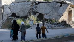 Lidé chodí v blízkosti zničených budov ve městě Idlib