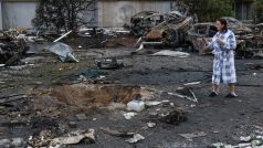 Obyvatelka stojí vedle zničených aut a poškozeného domu po útoku ruských dronů na Oděsu (fotografie z 9. listopadu 2024)