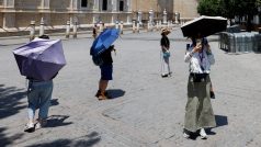 Turisté v Seville na jihu Španělska se chrání deštníky před sluncem
