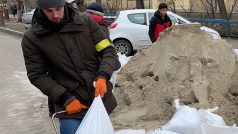 Lidé vyskladňují pytle s pískem a ukládají je do barikád bílé barvy