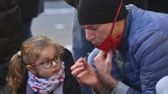 Lidé zapalují na Národní třídě svíčky a přinášení květinové věnce