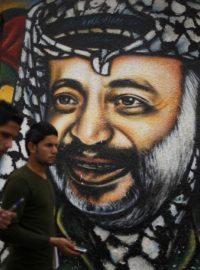 Palestinci v Gaze procházejí kolem portrétu Jásira Arafata