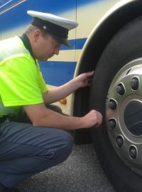 Policista kontroluje technický stav autobusu