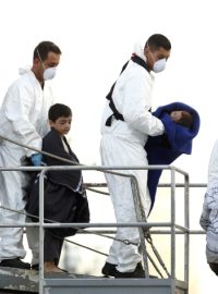 Policisté a vojáci pomáhají africkým migrantům vystoupit z lodi